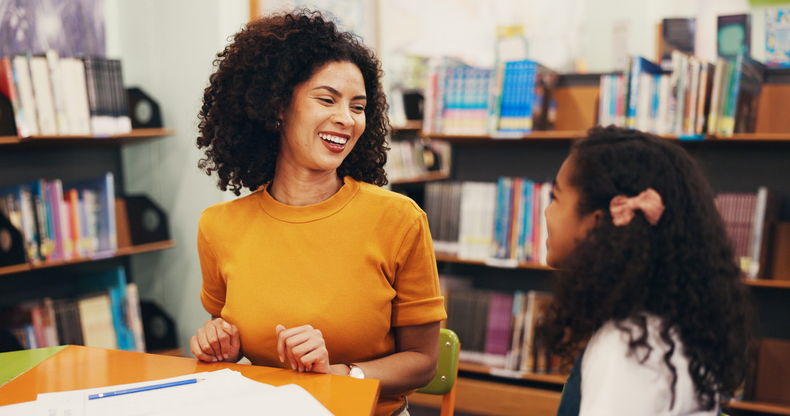 smiling-teacher-and-young-student-talking-in-a-lib-2026-06-01-18-59-28-utc